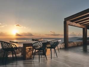 two chairs and a table on a balcony with the ocean at Vais Luxury Villas in Agios Nikolaos