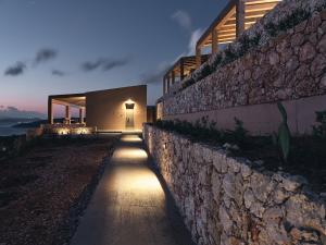 a pathway leading to a house with a stone wall at Vais Luxury Villas in Agios Nikolaos