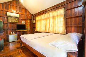 a bedroom with wooden walls and a bed in a room at Greenhouse resort in Buriram