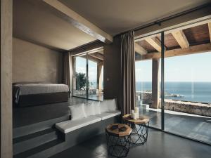 a bedroom with a bed and a couch and windows at Vais Luxury Villas in Agios Nikolaos