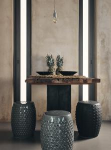 a table with three black stools with two plants on it at Vais Luxury Villas in Agios Nikolaos