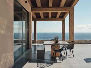 a dining room with a table and chairs and the ocean at Vais Luxury Villas in Agios Nikolaos