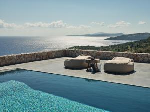 a pool with two beds and a view of the water at Vais Luxury Villas in Agios Nikolaos