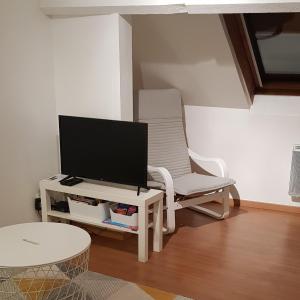 ein Wohnzimmer mit einem Stuhl und einem TV auf dem Tisch in der Unterkunft l’appart Malouin à 50M de la plage in Dunkerque