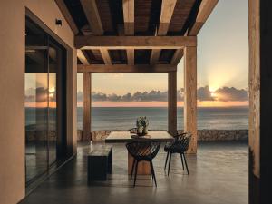 a dining room with a table and chairs and the ocean at Vais Luxury Villas in Agios Nikolaos