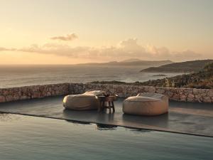 two beds on the edge of a pool with the ocean at Vais Luxury Villas in Agios Nikolaos