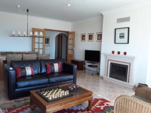 a living room with a black leather couch and a fireplace at See to Sea in Ericeira