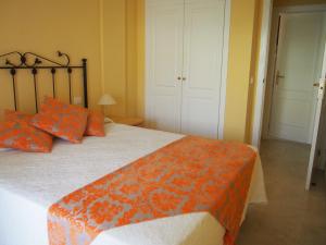 a bedroom with a bed with orange and white sheets and orange pillows at Maravilloso y tranquilo alojamiento en el Palm-Mar in Palm-mar