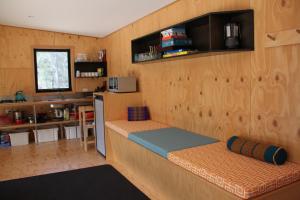 Binalong BayにあるBAY OF FIRES ECO HUT off grid experience at Binalong Bayのベッド付きの部屋、カウンター付きのキッチンが備わる客室です。