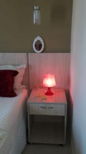 a red lamp on a night stand next to a bed at Flat no Aldeia das Águas (Deluxe) in Barra do Piraí
