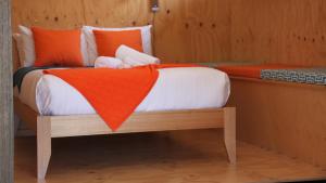 a bed with an orange blanket on top of it at BAY OF FIRES ECO HUT off grid experience at Binalong Bay in Binalong Bay