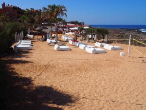 a sandy beach with white lounge chairs and the ocean at Maravilloso y tranquilo alojamiento en el Palm-Mar in Palm-mar