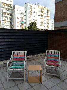 2 sillas y una mesa en un patio con edificios en Malabia Botanico en Buenos Aires