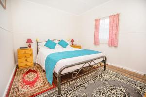 a bedroom with a bed and a dresser at Rosedale Cottages in Taranna