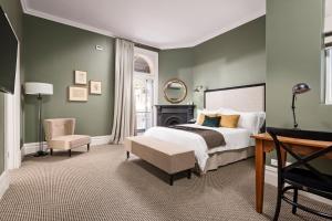 a bedroom with a bed and a desk and a chair at The National Hotel in Fremantle