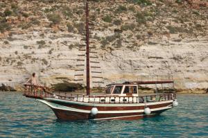 a boat sitting in the water next to a cliff at El Mosaico Del Sol in Lampedusa
