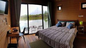 a bedroom with a large bed and a large window at Calm at Bangphat in Bor Saen