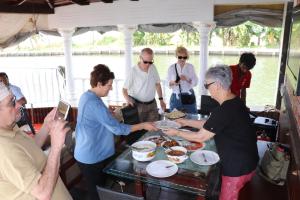 a group of people standing around a table with food at Marari White Home in Alleppey