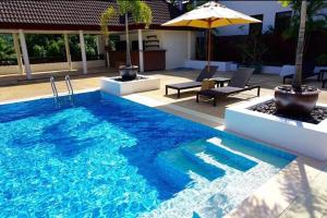 奈漢海灘的住宿－The Sands 2 bedroom apartment Naiharn，一个带桌子和遮阳伞的大型蓝色游泳池