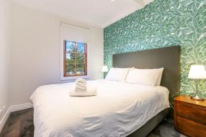 a bedroom with a white bed with a green accent wall at Bellevue Accommodation in Kiama