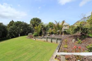 a yard with a fence and a grass field at Waipoua Lodge in Donnellys Crossing