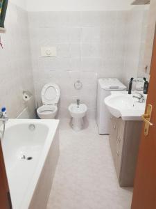 a white bathroom with a toilet and a sink at Parco Madonnetta in Acilia