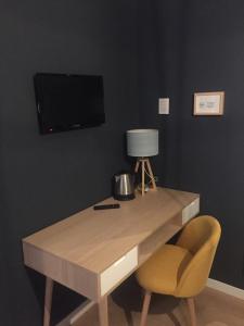 escritorio de madera con silla y TV en la pared en Ciccio Bed & Breakfast, en Bérgamo