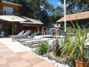 eine Terrasse mit Liegestühlen, einem Tisch und Personen in der Unterkunft Village Club Dunea in Soustons
