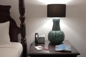 a lamp and a phone on a table next to a bed at Altamont West Hotel in Montego Bay