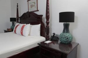 a bedroom with a bed and a lamp on a table at Altamont West Hotel in Montego Bay