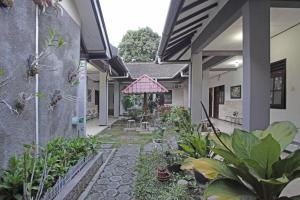a courtyard of a house with plants and a pink umbrella at RedDoorz @ Soekarno Hatta 2 in Malang