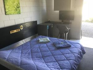 a bed with a blue comforter in a room at Rankins Springs Motel in Rankins Springs