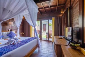 a bedroom with a bed and a desk and a television at Puri Pandawa Resort in Uluwatu