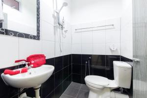 uma casa de banho com um WC branco e um lavatório. em Kampung Guest House em Pantai Cenang