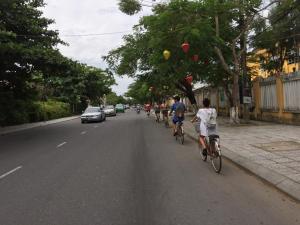 um grupo de pessoas andando de bicicleta por uma rua em Backhome Hostel & Bar em Hoi An
