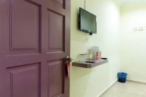 a door with a tv on the side of a room at Kampung Guest House in Pantai Cenang