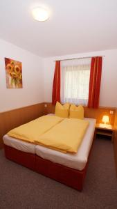 ツェル・アム・ツィラーにあるHaus Peter Schiestlのベッドルーム1室(黄色いシーツ付きのベッド1台、窓付)