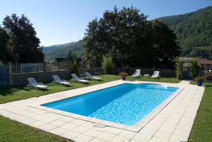 a swimming pool in a yard with chairs and a fence at Hôtel Burnichon in Tarare