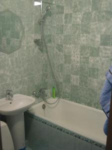 ein Badezimmer mit einem Waschbecken und einer Badewanne mit einer Dusche in der Unterkunft Apartment on Livoberezna metro station in Kiew