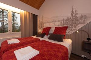 a bedroom with two beds with red and white sheets at Hotel Ylläsrinne in Ylläsjärvi