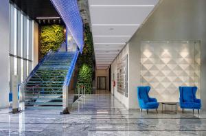korytarz z niebieskimi krzesłami i schodami w budynku w obiekcie Apartamenty Vola Residence w Warszawie
