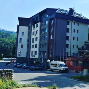 a large building with a van parked in a parking lot at Стаи за гости Топ Старс Смолян in Smolyan
