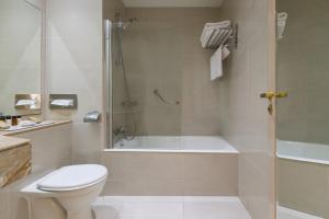 a bathroom with a tub and a toilet and a shower at Golden Bay Beach Hotel in Larnaca
