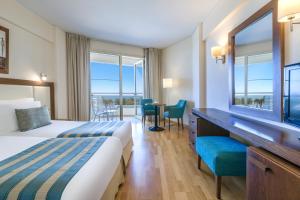 a hotel room with a bed and a table and chairs at Golden Bay Beach Hotel in Larnaca