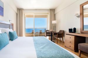 a hotel room with a bed and a view of the ocean at Golden Bay Beach Hotel in Larnaca