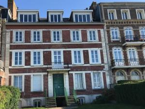 Un viejo edificio de ladrillo con ventanas blancas y una puerta. en Sunset Dieppe, en Dieppe
