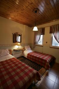 a bedroom with two beds and a wooden ceiling at Villa Filokosta in Pertouli