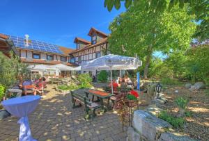 een patio met mensen aan tafels en een parasol bij Hotel Kuchalber Hof in Donzdorf