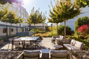 patio ze stołami, krzesłami i drzewami w obiekcie Pullman Basel Europe w Bazylei