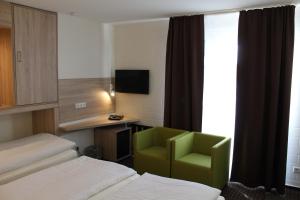 a hotel room with a bed and a green chair at Pur Hotel in Emlichheim